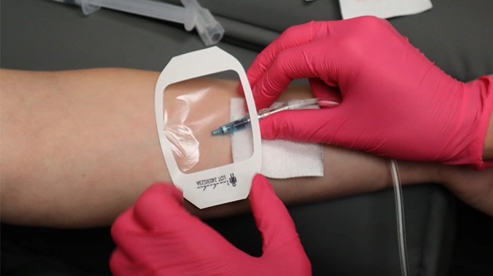 Chiropractor Towson MD injection into a patient’s arm using a syringe, with a small bandage being placed over the injection site.