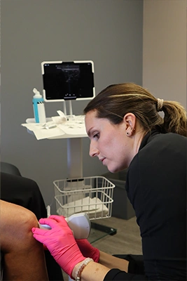 Caroline Chell inspecting a patient's knee with a medical eletronic tool.